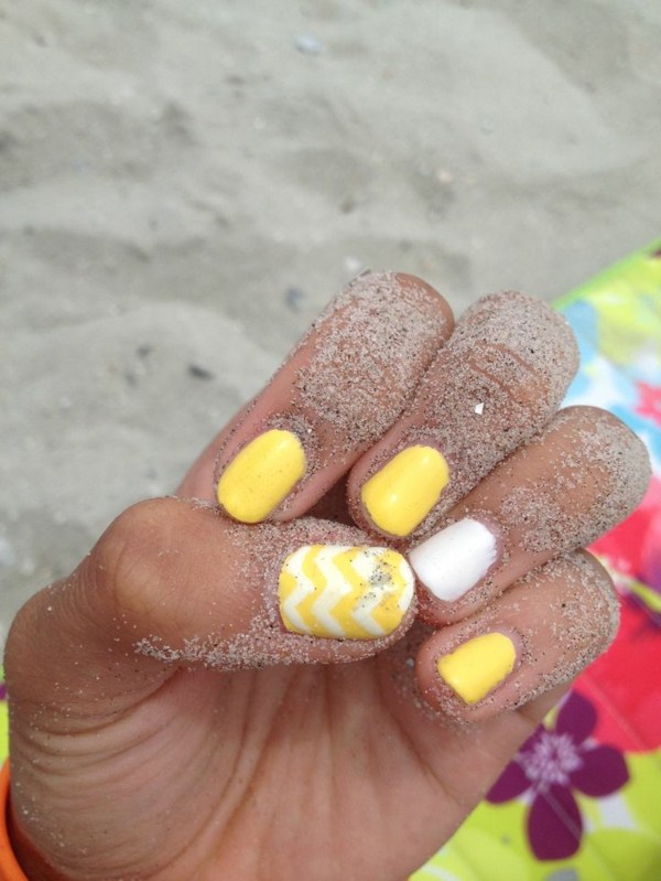 Gula naglar-sand-strand-handduk-sand-på-hand