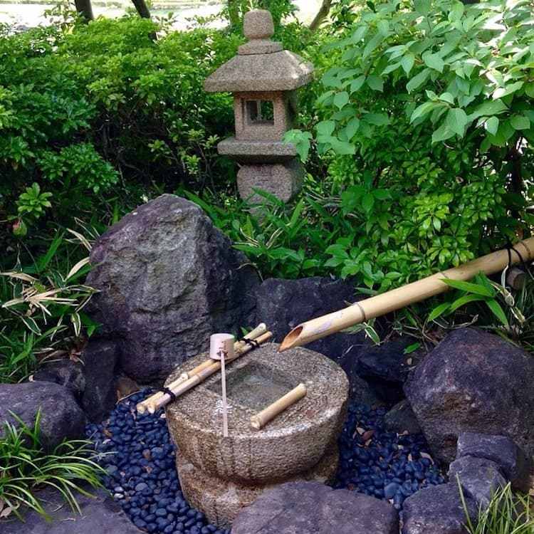 Japansk vattenfunktion med stenar, småsten och bambu