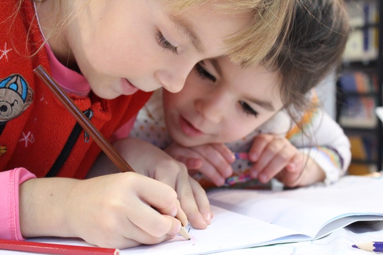 Skolbarn flickor tillbaka till skolan skriva penna klasskamrater