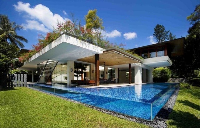 Glasfiber-pool-byggnad-transparent-sidoväggar-kant-flodstenar-modern-villa