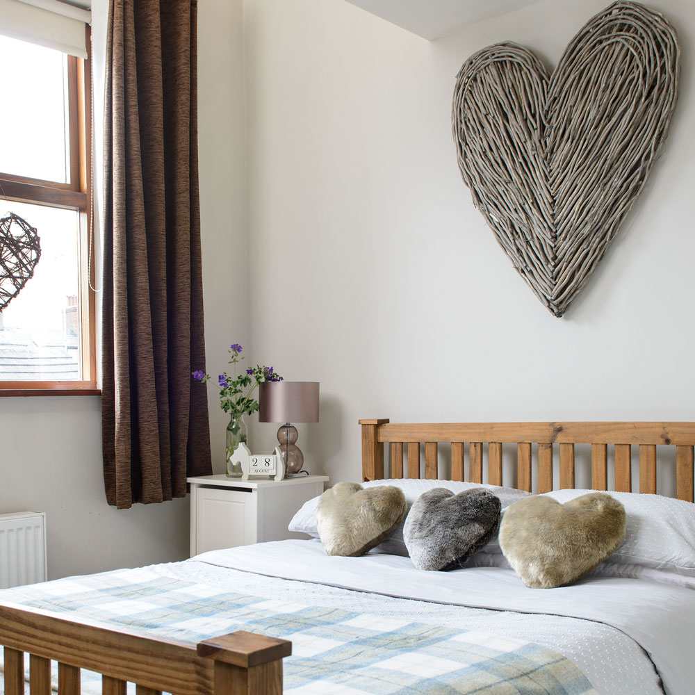 Smalt utrymme för sovrummet med ett hjärta som dekoration på väggen och som kudde