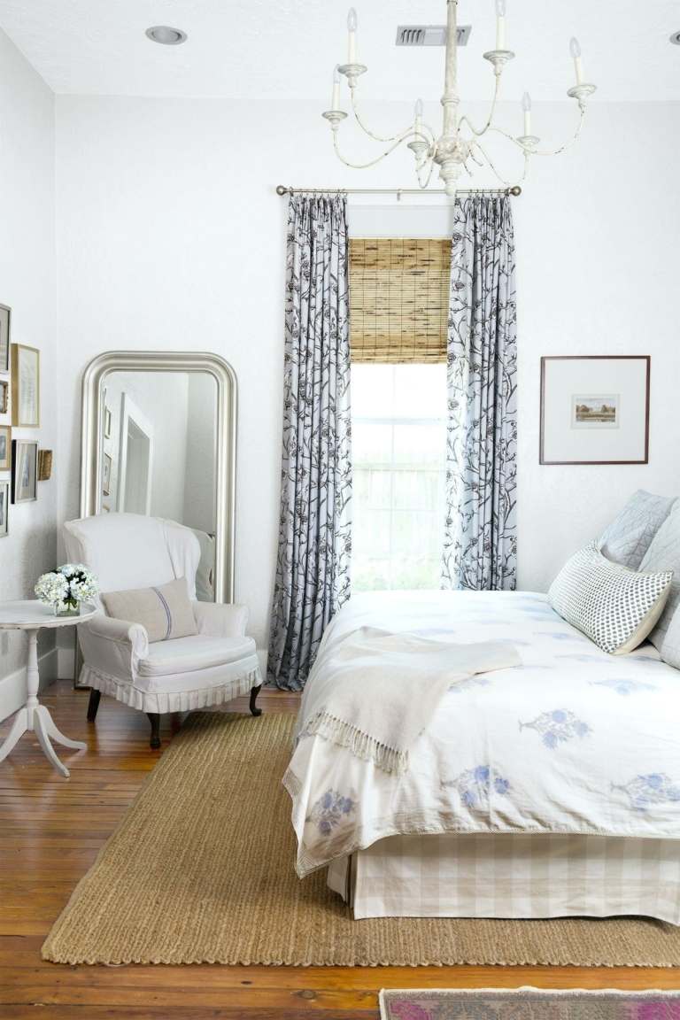 Romantiskt rum i lantlig stil med fåtölj och spegel, sidobord och gardiner som dekoration