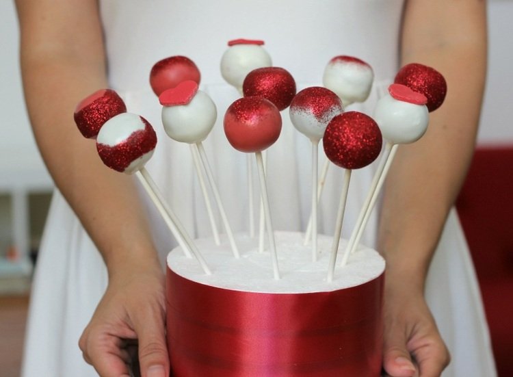 dessert-nyårsafton-tårta-pops-röd-vit-glitter-socker-hjärta-ätpinnar-hållare-kvinna-klänning-vit