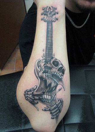 Κρανίο που παίζει τατουάζ κιθάρας στο δεξί χέρι