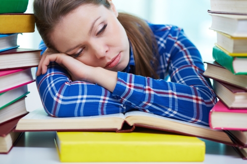 Κουρασμένος μαθητής που κοιμάται πάνω από σχολικά βιβλία