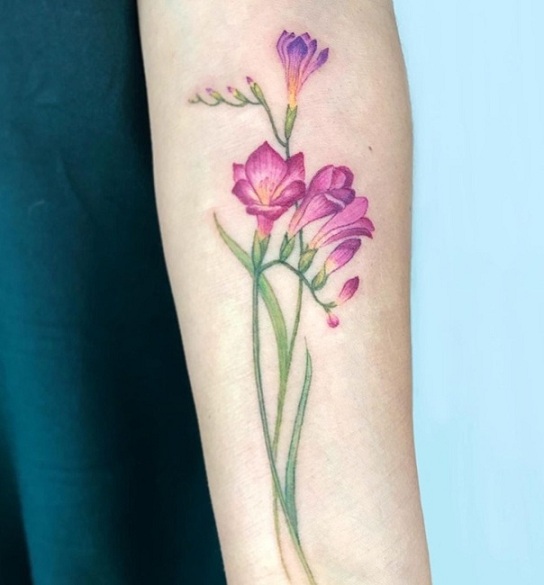 Violetti freesia -tatuointi kyynärvarressa