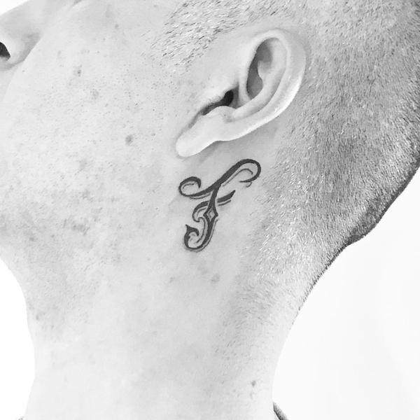 Κομψό τατουάζ F γράμματος κοντά στο αυτί