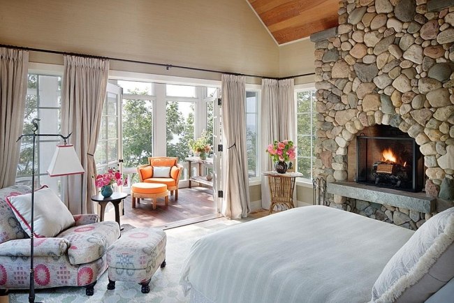Säng sovrum natursten vägg inbyggd öppen spis blommotiv orange fåtölj michigan-lake house