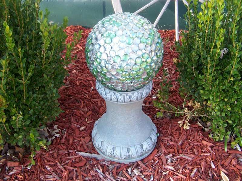 Trädgård-dekoration-glas-boll-piedestal-mellan-häck-växter