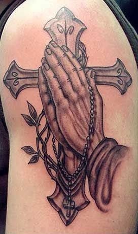 Risti taitettujen käsien tatuoinnilla