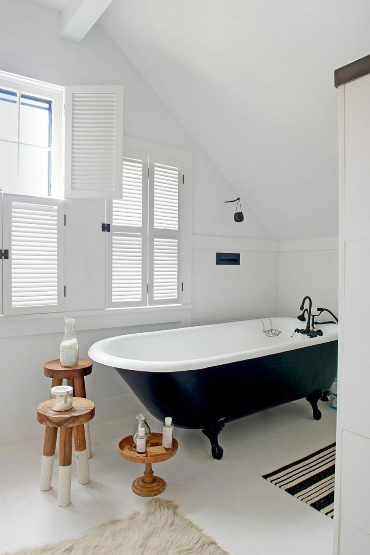 badrum med sluttande tak retro badkar svartvita sidobord badmattor