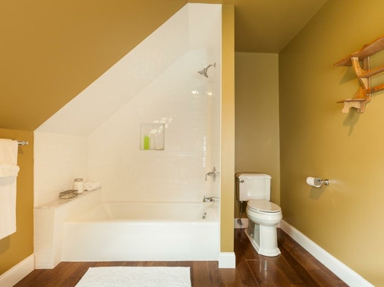 badrum med sluttande tak ockra väggfärg vit badkarsparkett