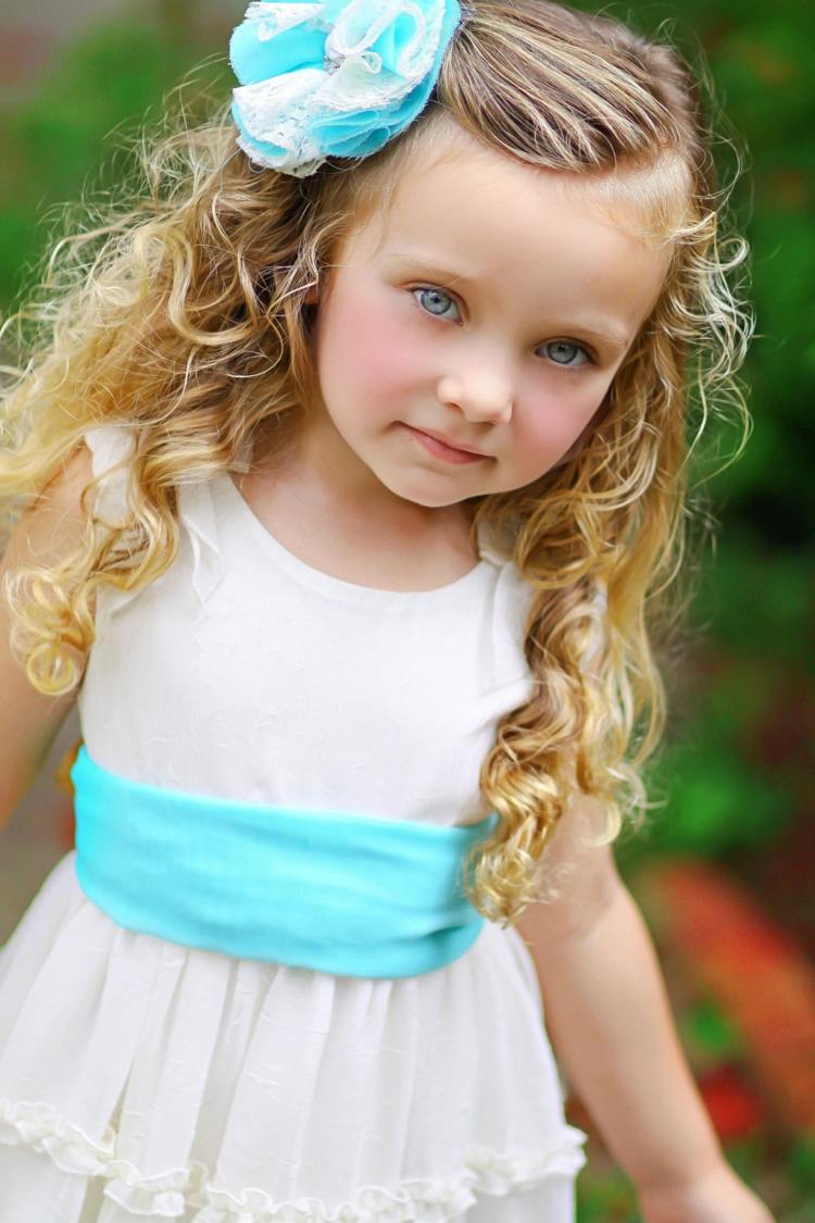 barns frisyrer för flickor lockar rosett ljusblå klänning vitt bälte