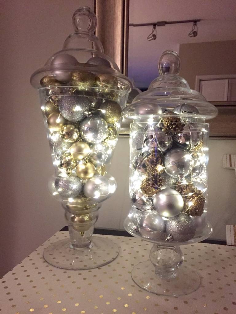 Juldekoration i ett glas med sagoljus och julgransbollar i guld och silver