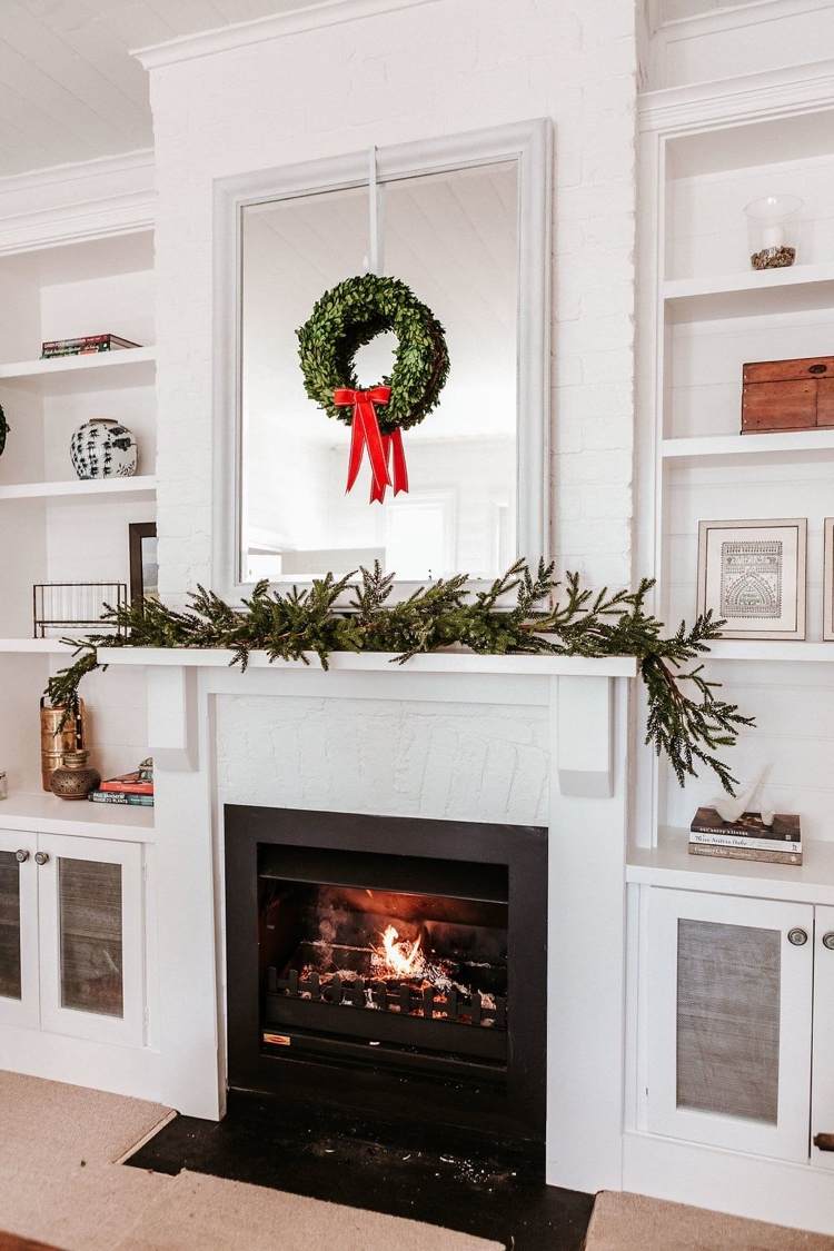 Mantelpiece minimalistisk dekorerad till jul med grangrenar och en buxbalkrans