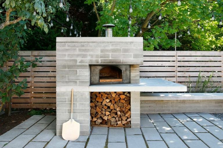 Betong i trädgården för grillen med ett fack för veden och tallrikar som golvbeläggning