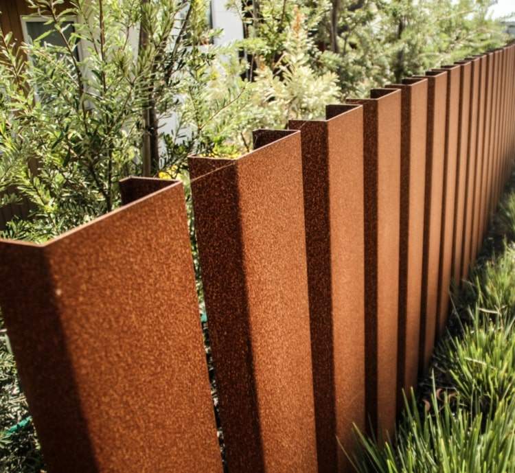 Rustade stålbalkar som en skärm och staket i cortenstål i trädgården