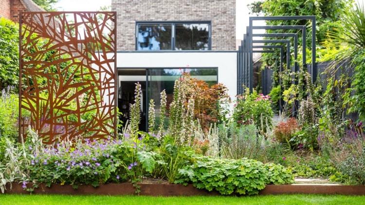Dekorativ sekretessskärm i en naturlig trädgård i ett minimalistiskt hus