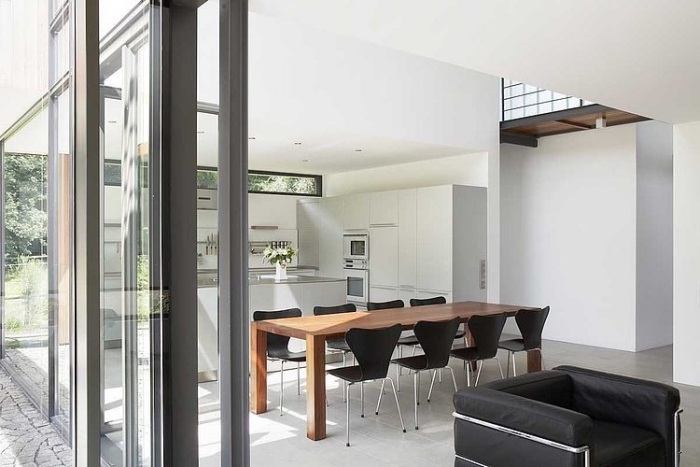 modern-lägenhet-vit-vägg-färg-matplats-plats-massivt trä-bord-stolar-svart-sits