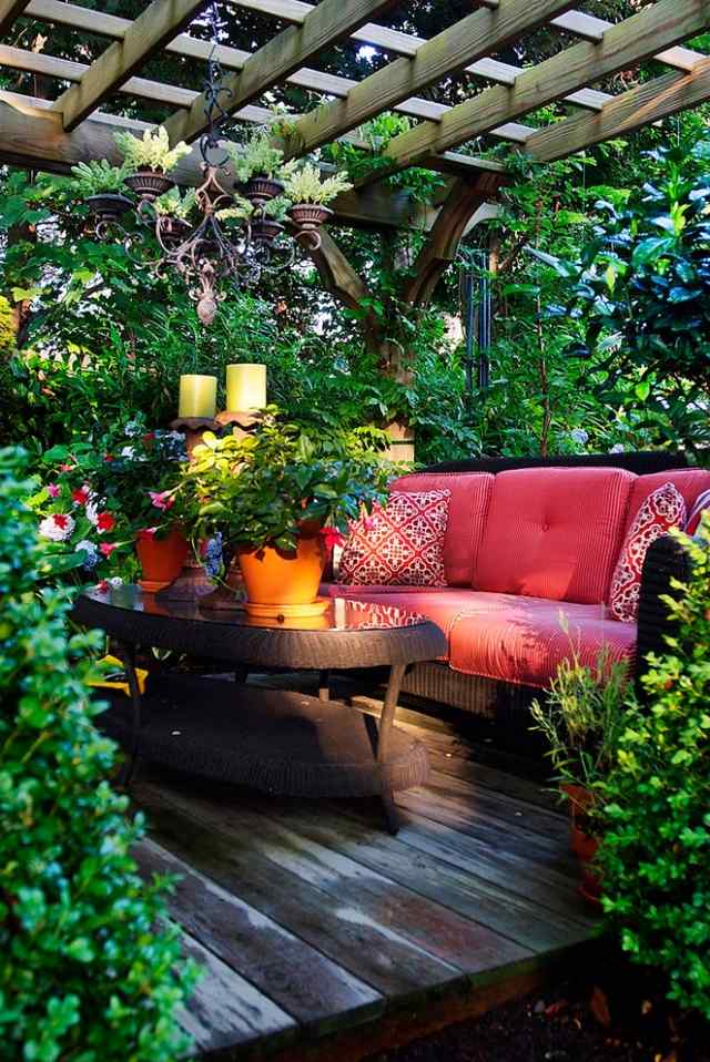 trä pergola i trädgården gröna växter sekretess skärm soffa rotting rosa kuddar
