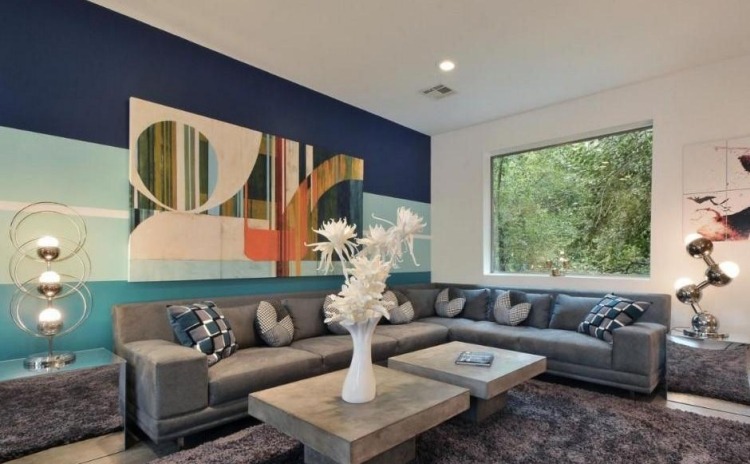 möbleringsidéer-vardagsrum-mysigt-hörn-soffa-grå-kuddar-väggdekoration-bild-blå-fönster-matta