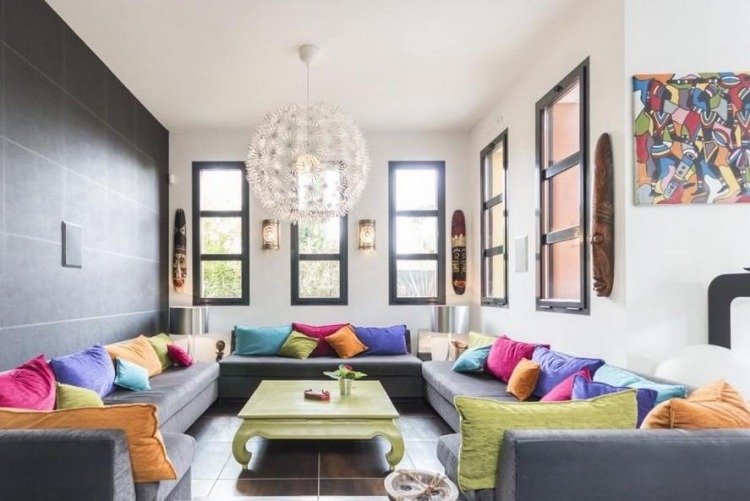 möbleringsidéer-vardagsrum-mysiga-grå-soffa-kuddar-färgglada-soffbord-gröna-fönster