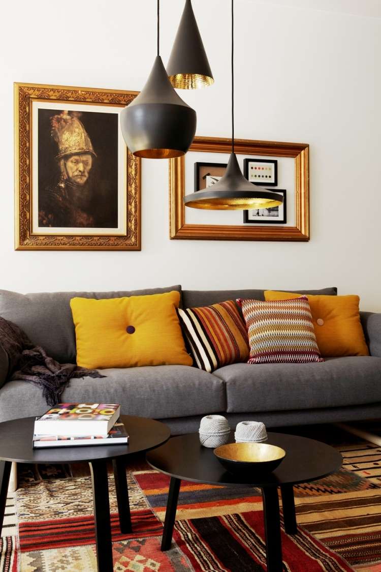 möbleringsidéer-vardagsrum-mysiga-soffa-grå-kuddar-mattor-bilder-hängande-lampor-varma färger