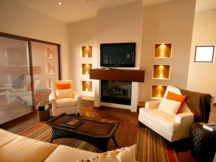 möbleridéer-vardagsrum-brun-varm-färg-matta-fåtölj-öppen spis-soffbord-ratan-indirekt-belysning-grädde-vita stoppade möbler