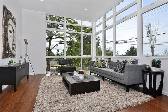 vardagsrum-golv-till-tak-fönster-möbler-grå-svart-trägolv