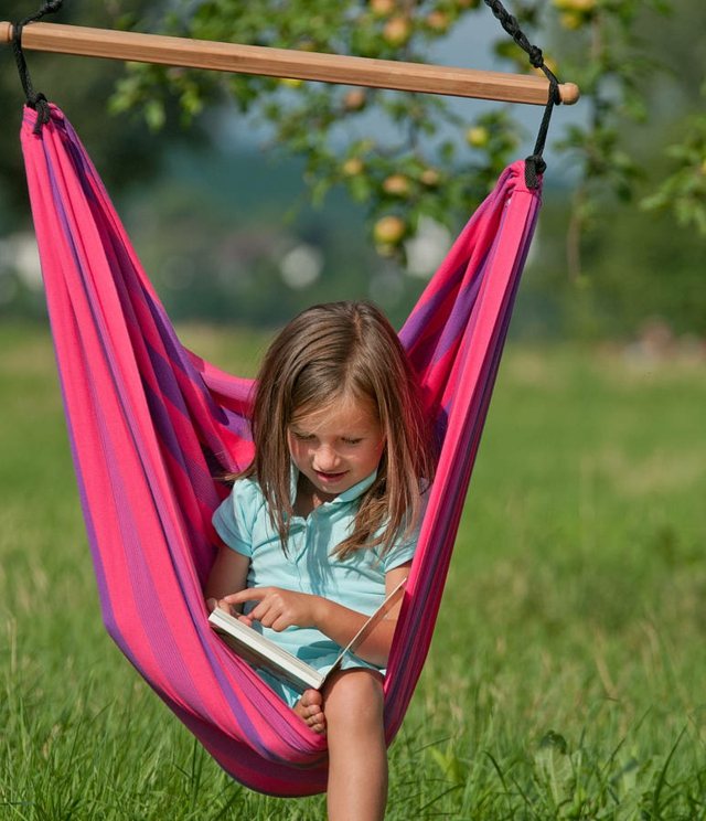 Flicka i hängmatta som läser utomhus gräsmatta