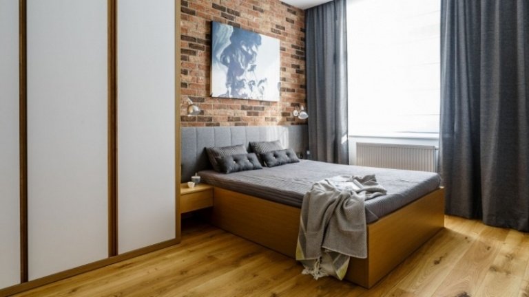 modern-sovrum-röd-tegel-vägg-trä-golv-grå-gardiner-säng-sänggavel