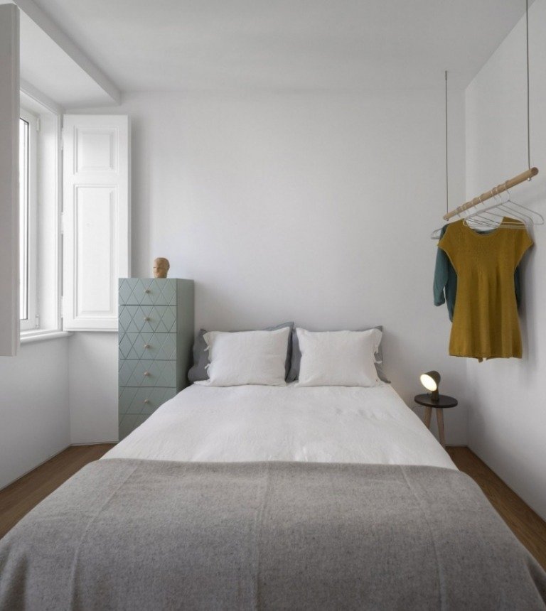 litet sovrum-vitmålat-vägghängande-klädstång-hög byrå