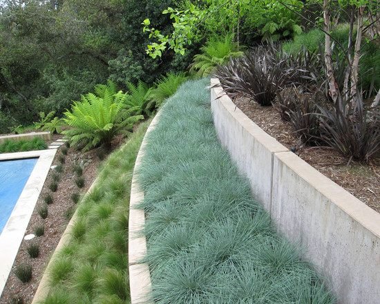 Trädgårdens kuperade landskap förstärker med stödmurar i betongmurverk