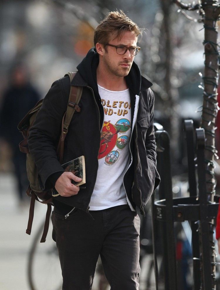 ryan gosling med en ryggsäckstryckt t-shirt, avslappnad jacka och hoodie på gatan