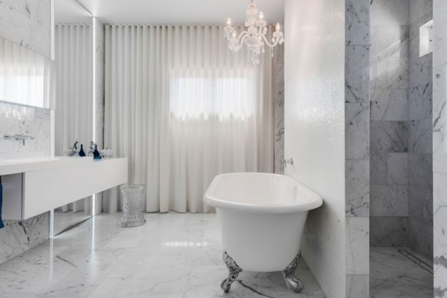lyxigt badrum marmor vit ljuskrona rena gardiner duschkabin
