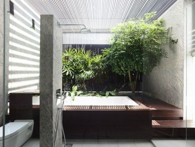 wellness badrum sten optik väggbyggnad badkar växter glas tak sol