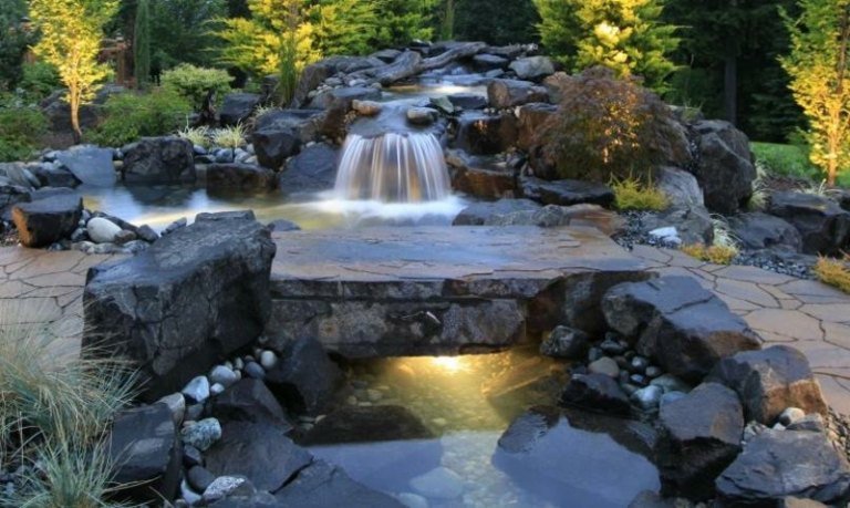 Vattenfall-bäck-bro-natursten-trädgård stig-träd-belysning
