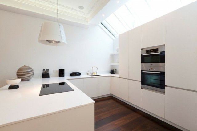 U-form-kök-med-vit-yta-kokplatta-och-hängande-ljus