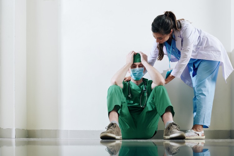 Sjuksköterska lugnar ner desperat kirurg efter operation på sjukhus med munskydd