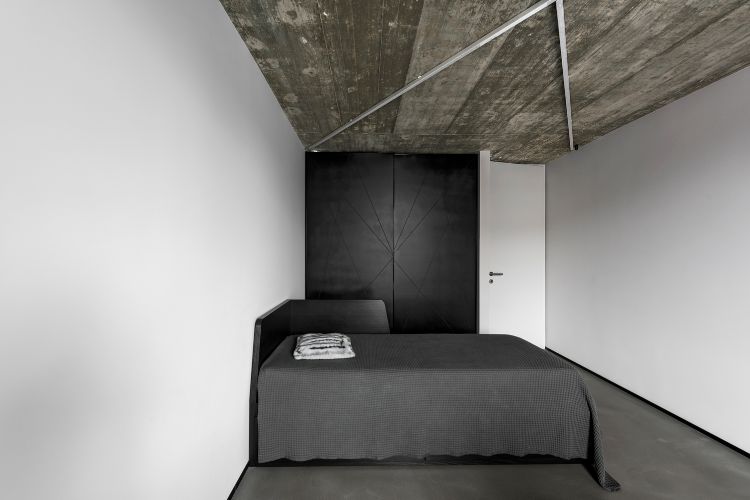 säng täckt kuddrum grå svart garderob elegant minimalistisk belysning