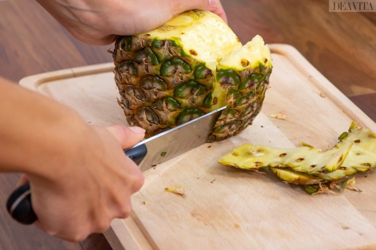 Skala och skär ananas med en stor kniv och följ konturerna