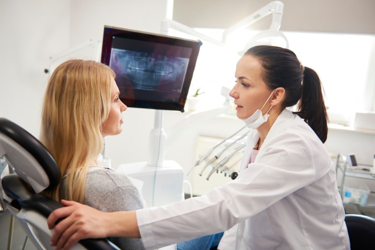 Tandläkare lugnar patienten under läkarundersökningen förhindrar tandläkarskräck