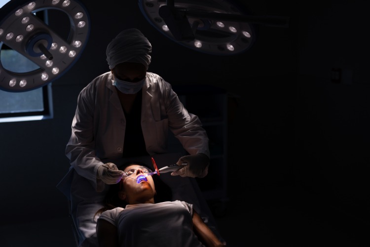 Tandvård utförs i det mörka rummet hos patienten med rädsla för tandläkare
