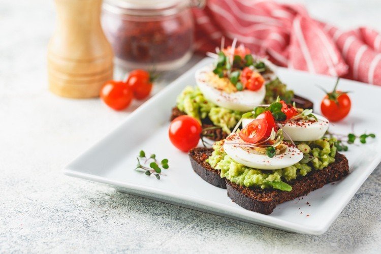 Pumpernickelbröd för hälsosam avokado toast med ägg och körsbärstomater