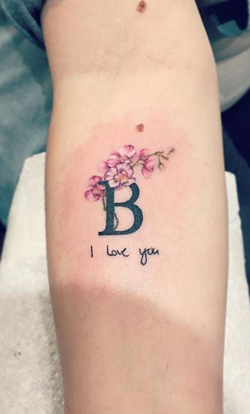 B -kirjain tatuointi kukilla