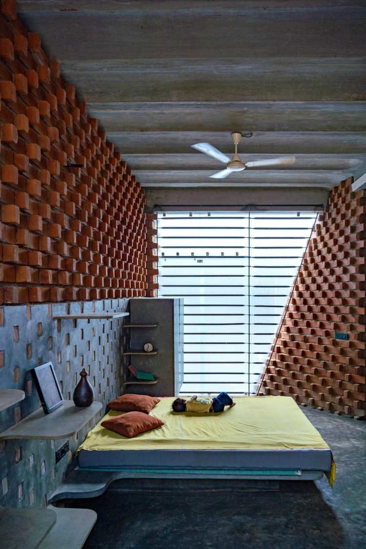 Småbarn sover på en säng i ett ovanligt barnrum av tegel och cement