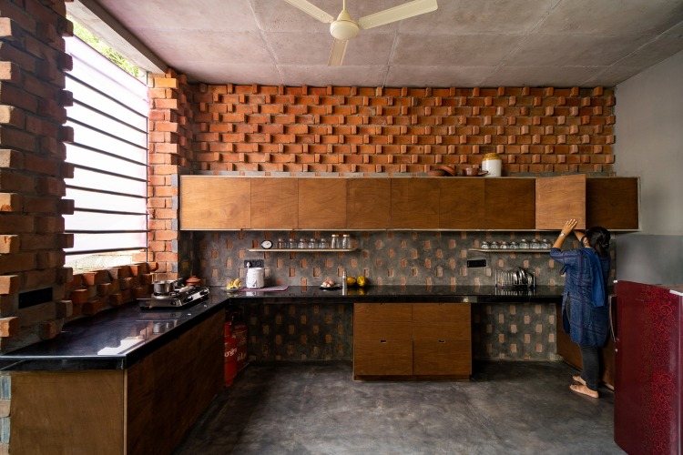 hemmafru använder träskåpen i ett kök med en tegelvägg inuti och betongväggbeklädnad