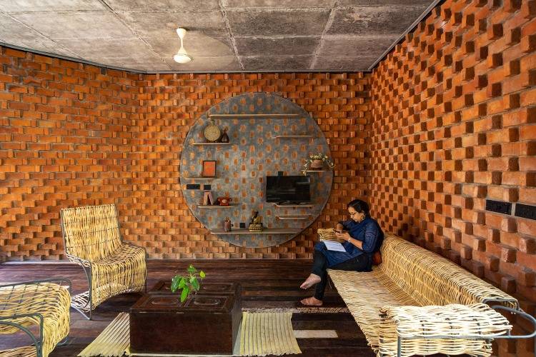 Kvinna som sitter på återvunna möbler i vardagsrummet med dekorerad tegelvägg inuti