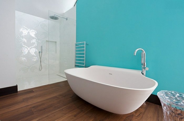 modernt badrum runt badkar trägolv turkos dusch