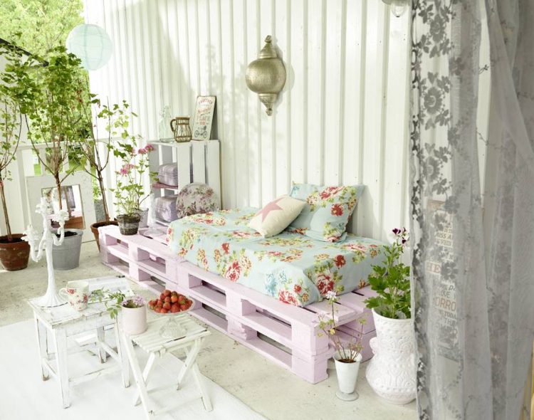 Balkongsoffa av pallar målade rosa blommiga kuddar